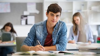 Smiling student guy preparing for exam at school