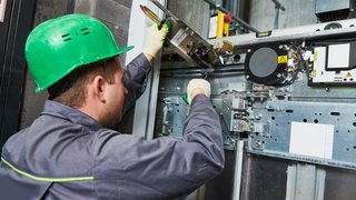 lift machinist adjusting elevator mechanism
