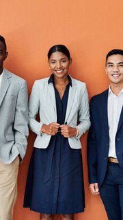 Portrait of a group of businesspeople standing together against an orange background