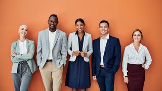 Portrait of a group of businesspeople standing together against an orange background