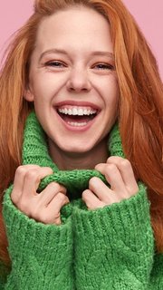 Bright laughing teenage girl on pink background