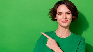 Photo of shiny cute woman wear casual t-shirt pointing finger empty space isolated green color background