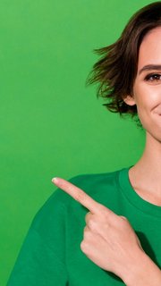 Photo of shiny cute woman wear casual t-shirt pointing finger empty space isolated green color background