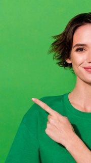 Photo of shiny cute woman wear casual t-shirt pointing finger empty space isolated green color background