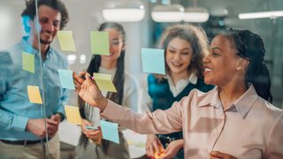 Business team brainstorming and planning using sticky notes on glass wall