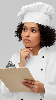 thinking female chef with clipboard and pen