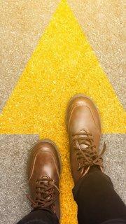 Feet and arrows on road background in starting line beginning idea. Top view. Woman in leather ankle boots on pathway with yellow direction arrow symbol. Moving forward, new start and success concept.
