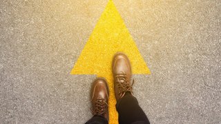 Feet and arrows on road background in starting line beginning idea. Top view. Woman in leather ankle boots on pathway with yellow direction arrow symbol. Moving forward, new start and success concept. Feet and arrows on road background in starting line beginning idea. Top view. Woman in leather ankle boots on pathway with yellow direction arrow symbol. Moving forward, new start and success concept.