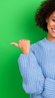 Photo of funny nice girl curly hairstyle wear blue sweater directing empty space promo news sale isolated on green color background