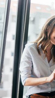 Attractive businesswoman using a digital tablet while standing in front of windows